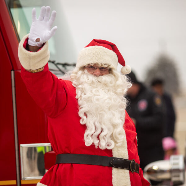 Santa waving in front of a red truck