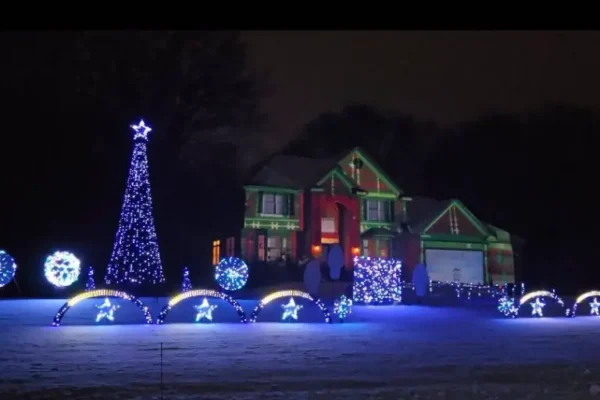 Twin Cities Gateway holiday light display 2025 featuring a home decorated with colorful Christmas lights and lit trees in the snow.