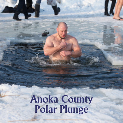 A man submerged chest-deep in icy water through a cut-out hole in the ice, shivering with his hands up. Bystanders stand on the snow-covered ice in the background. Text at the bottom reads: Anoka County Polar Plunge.
